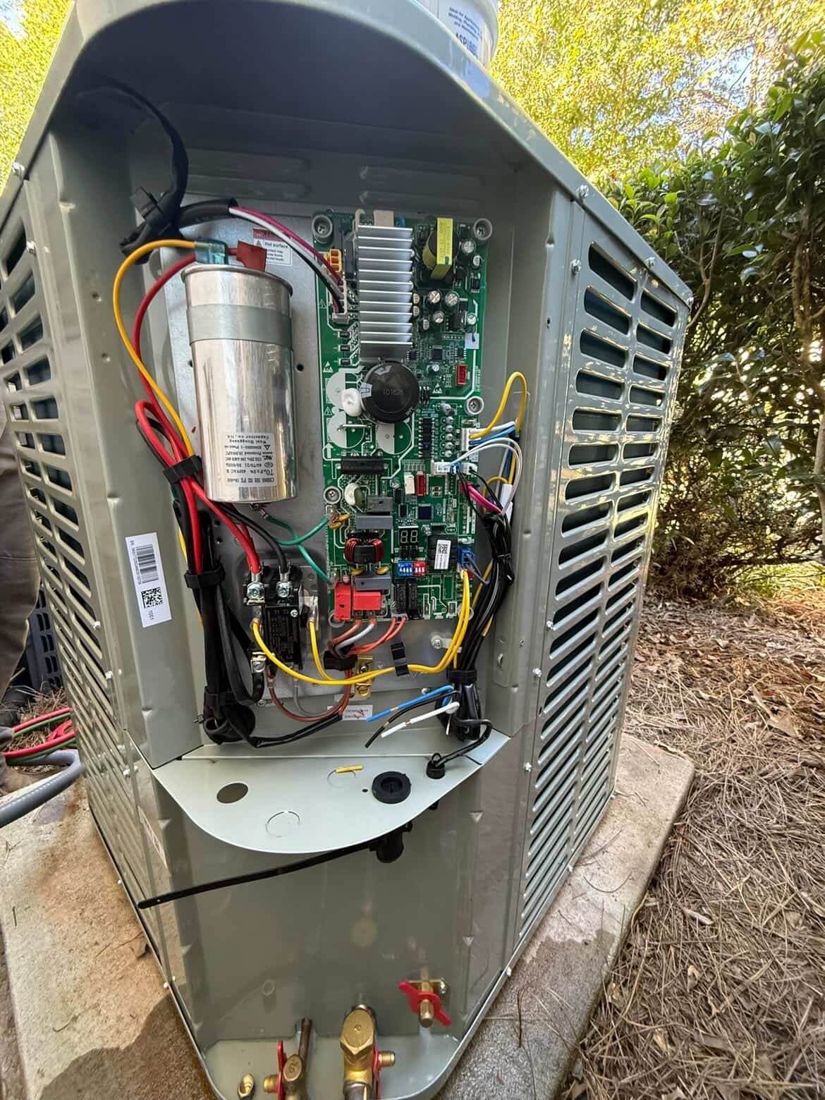 HyperTemp HVAC technician servicing an outdoor heat pump unit