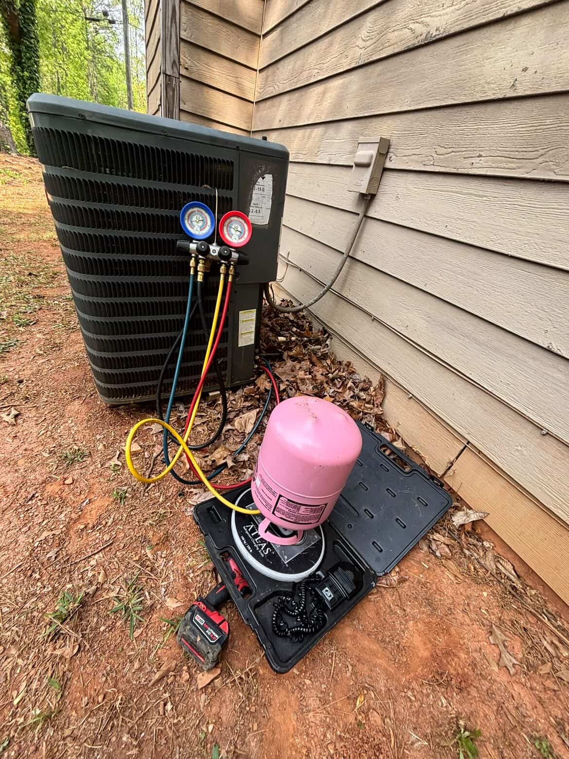 HyperTemp HVAC technician charging refrigerant on an outdoor AC condenser